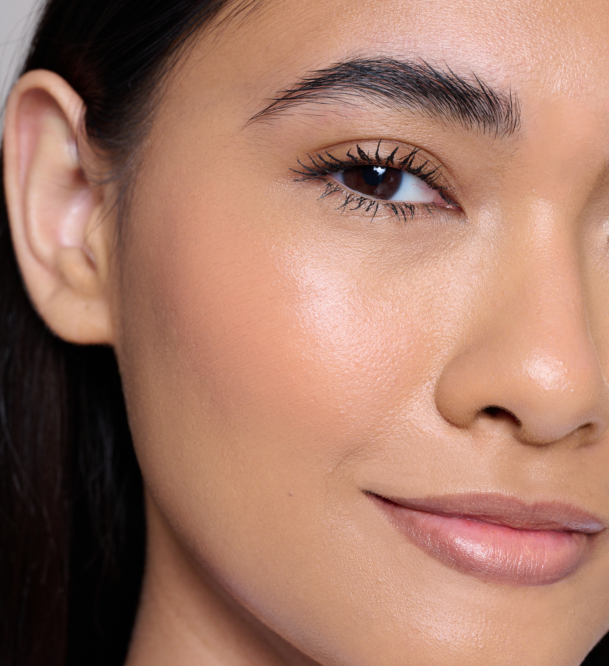 Model wearing Skin Loving BB Cream, Feature Length Lash Lover mascara, Cheek Veil Liquid Blush in Aura and Beautifing Brow Wand