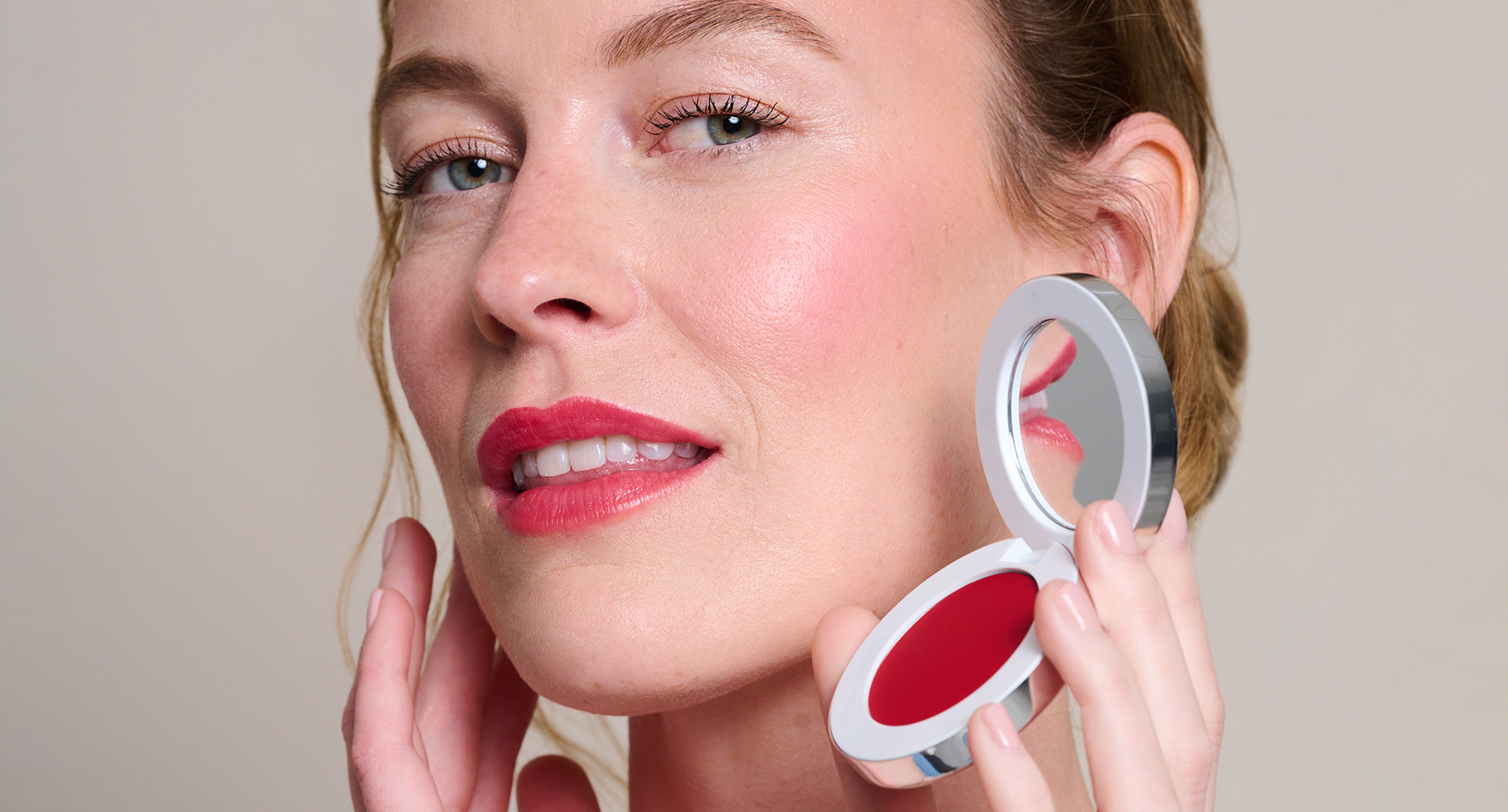 Model holding and wearing Colour Wonder Lip and Cheek Balm in shade Rebel Red