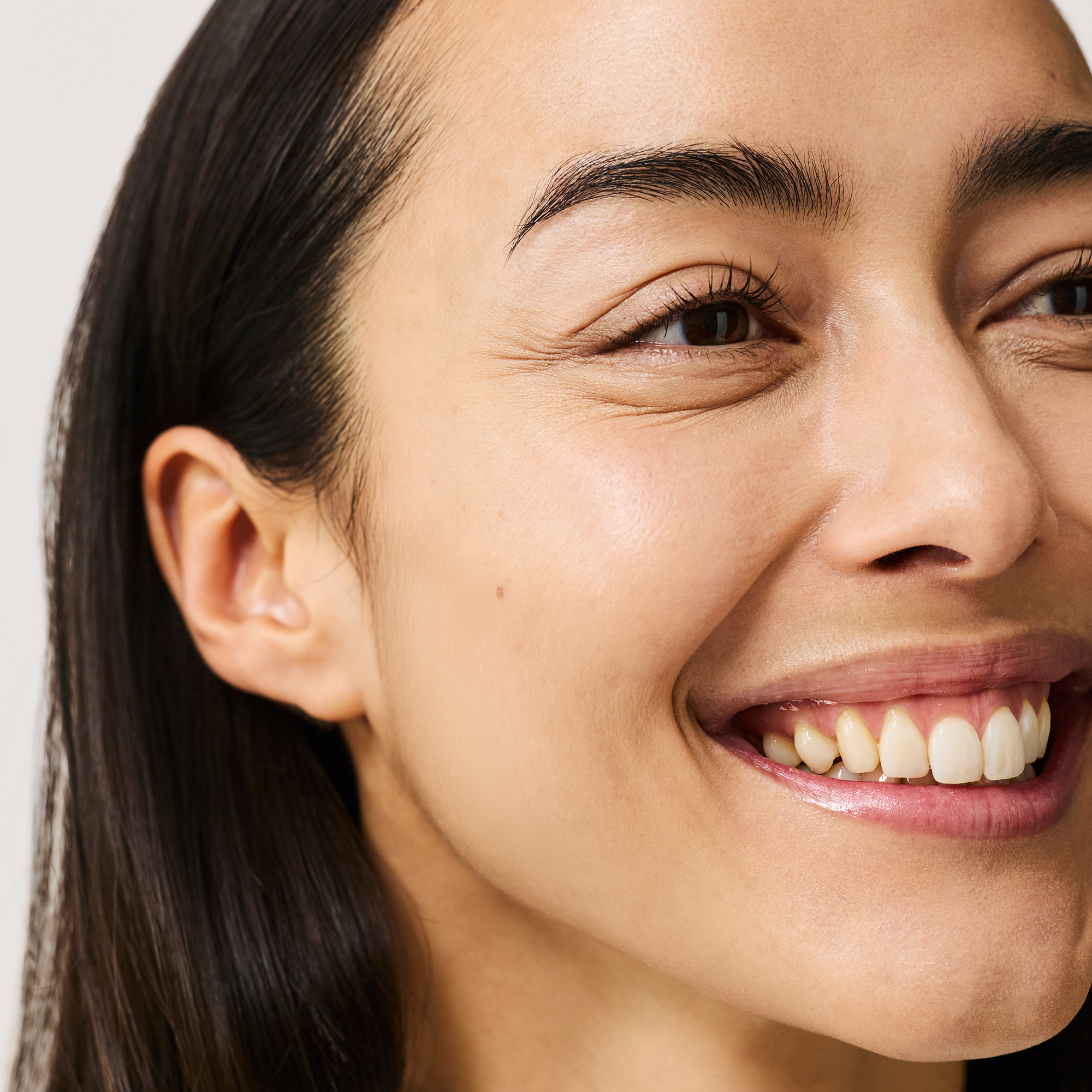 Model wearing Hydraveil Serum Foundation in shade 7, Skin Perfecting Concealer in shade 7, Irresistible Face Base in shade 1 and Finishing Clear Brow Gel