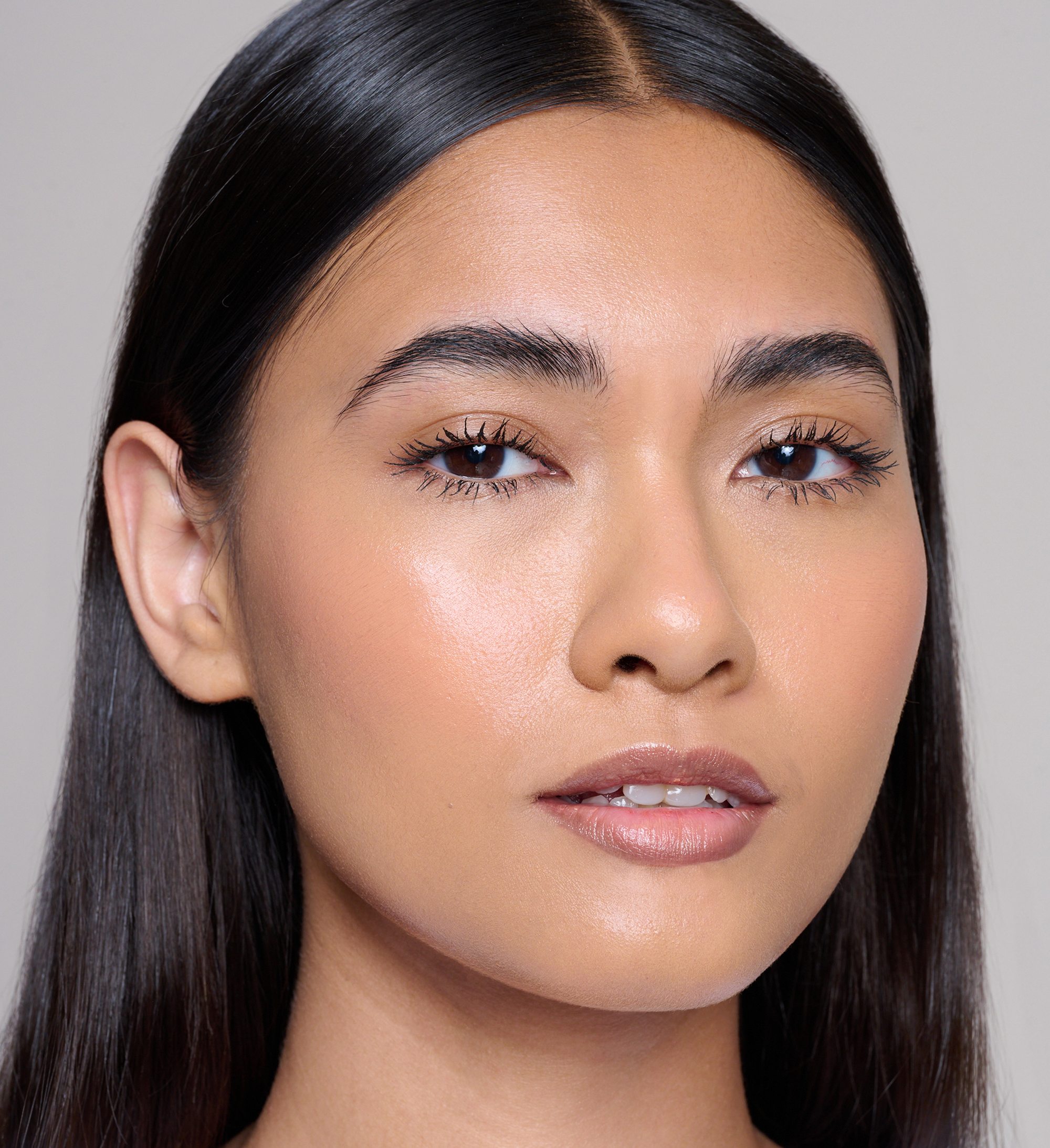 Model wearing Skin Loving BB Cream, Feature Length Lash Lover mascara, Cheek Veil Liquid Blush in Aura and Beautifing Brow Wand