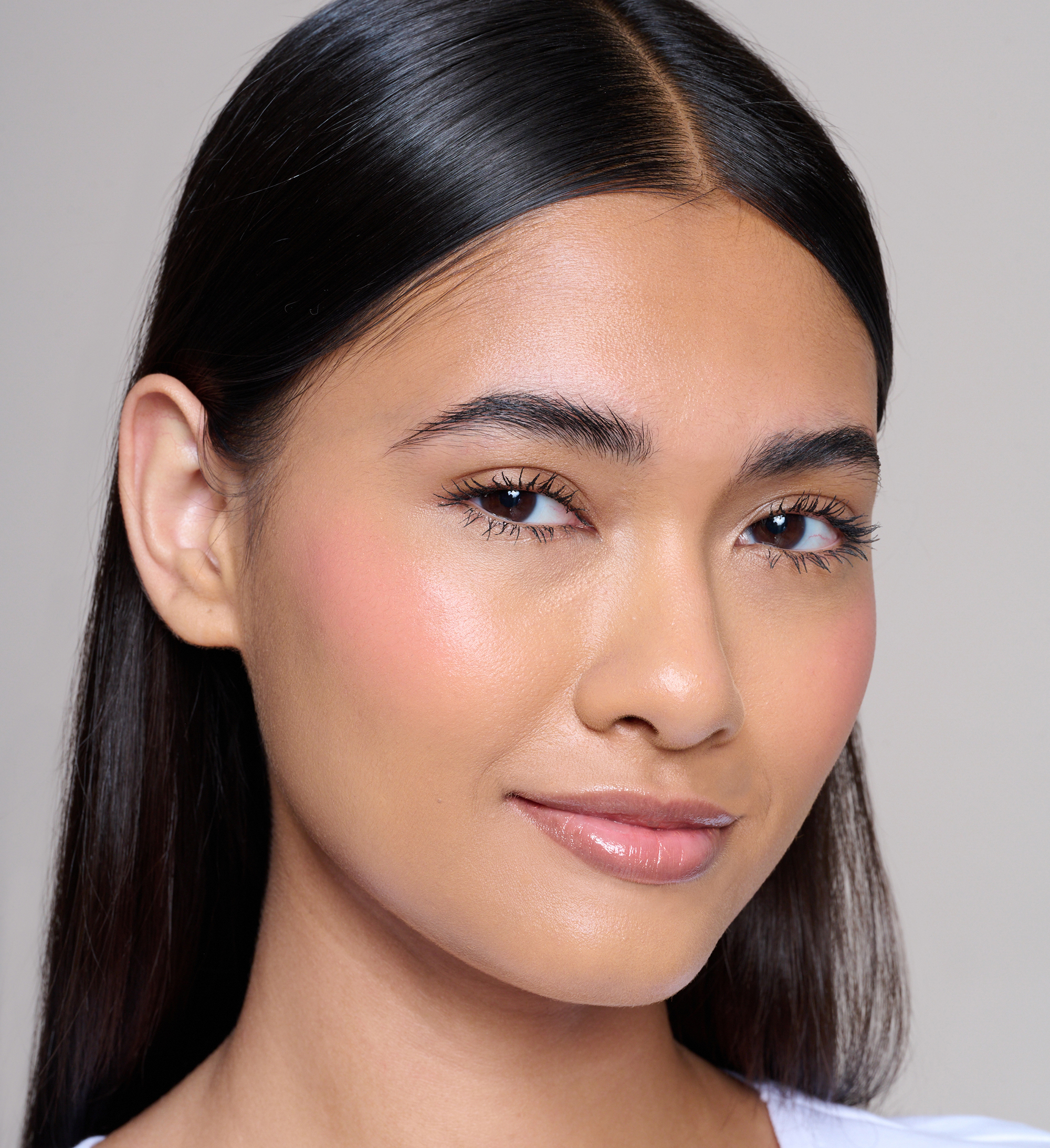 Model wearing Skin Loving BB Cream, Feature Length Lash Lover mascara, Cheek Veil Liquid Blush in Paradise and Beautifying Brow Wand