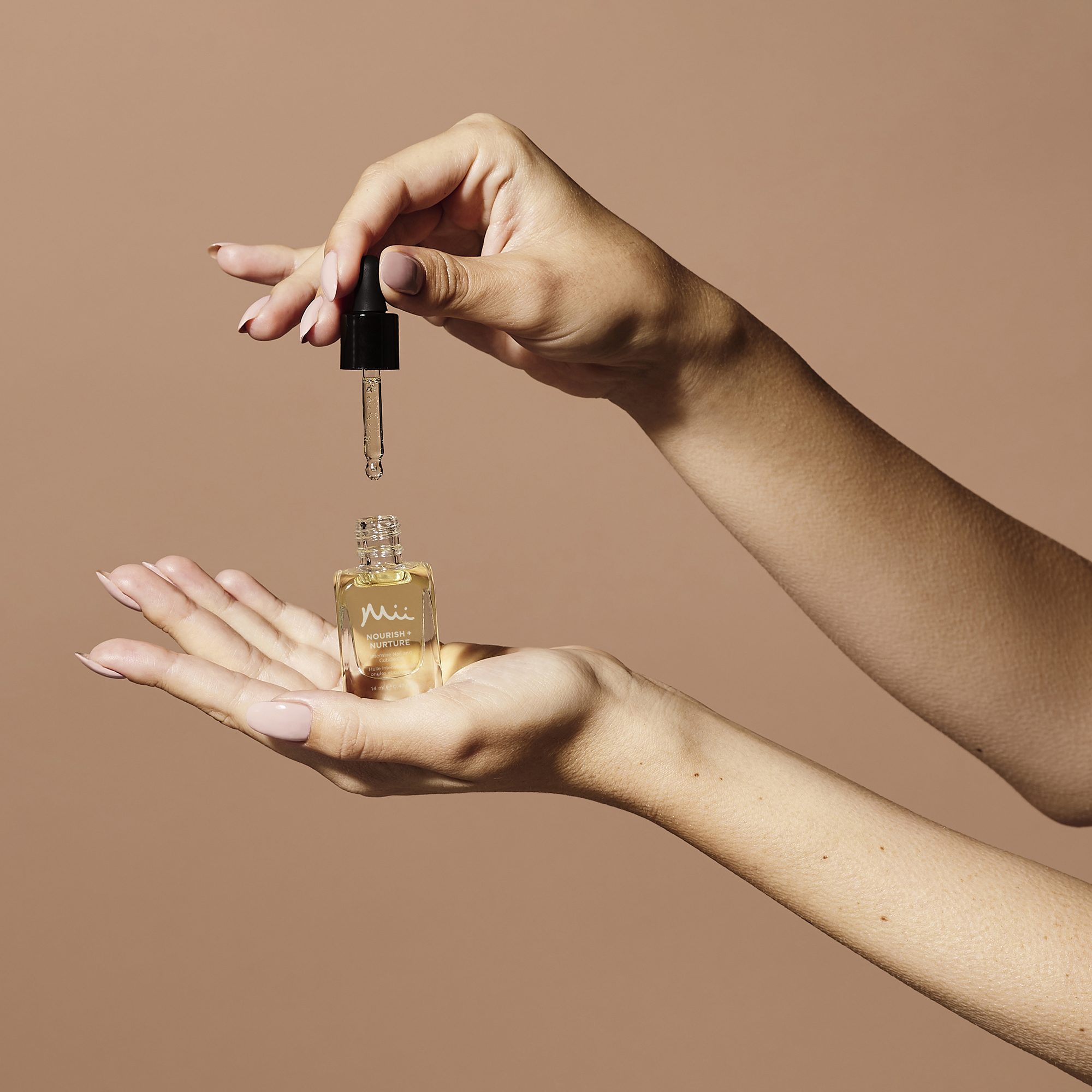 Model holding Nourish + Nurture Nail and Cuticle Oil