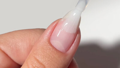 Hand applying base coat onto nail
