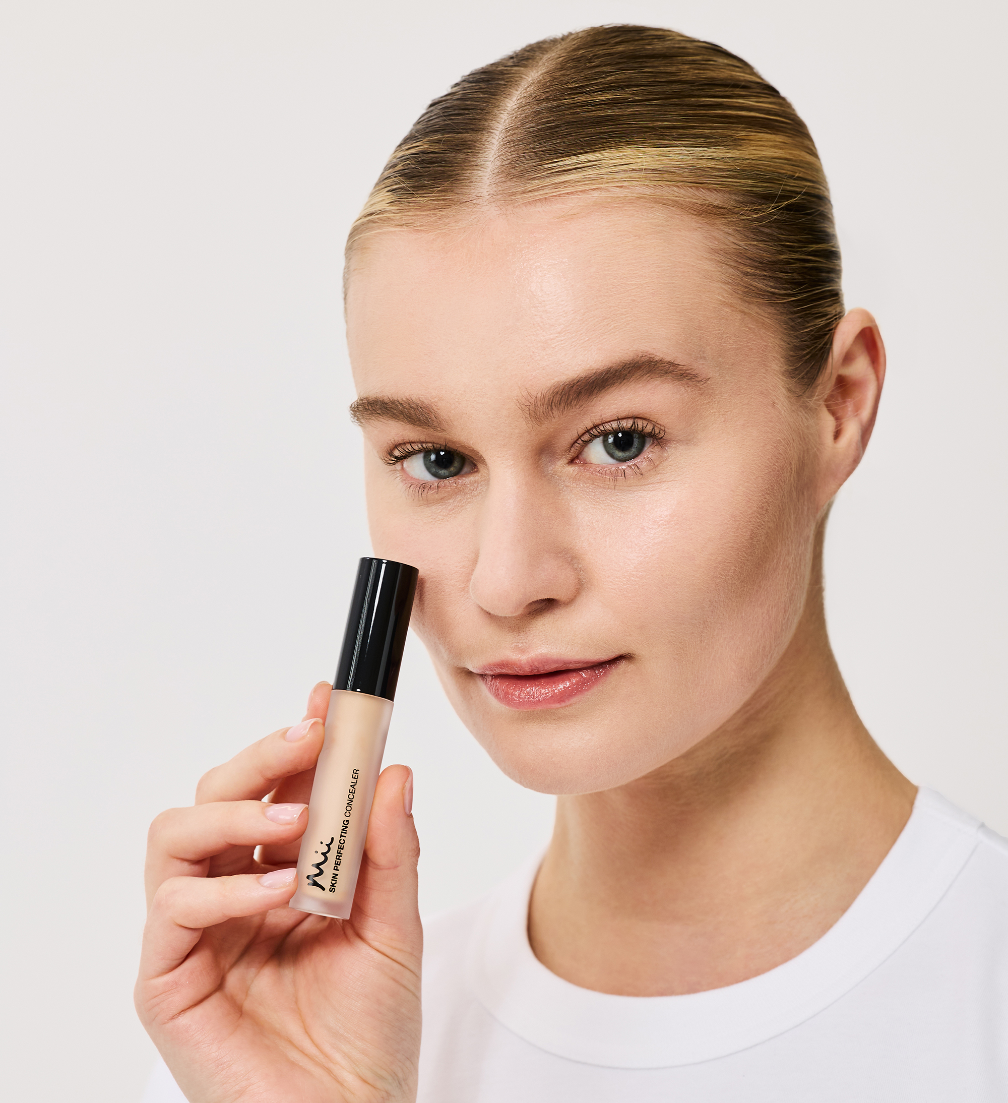 Model wearing and holding Skin Perfecting Concealer in shade 3