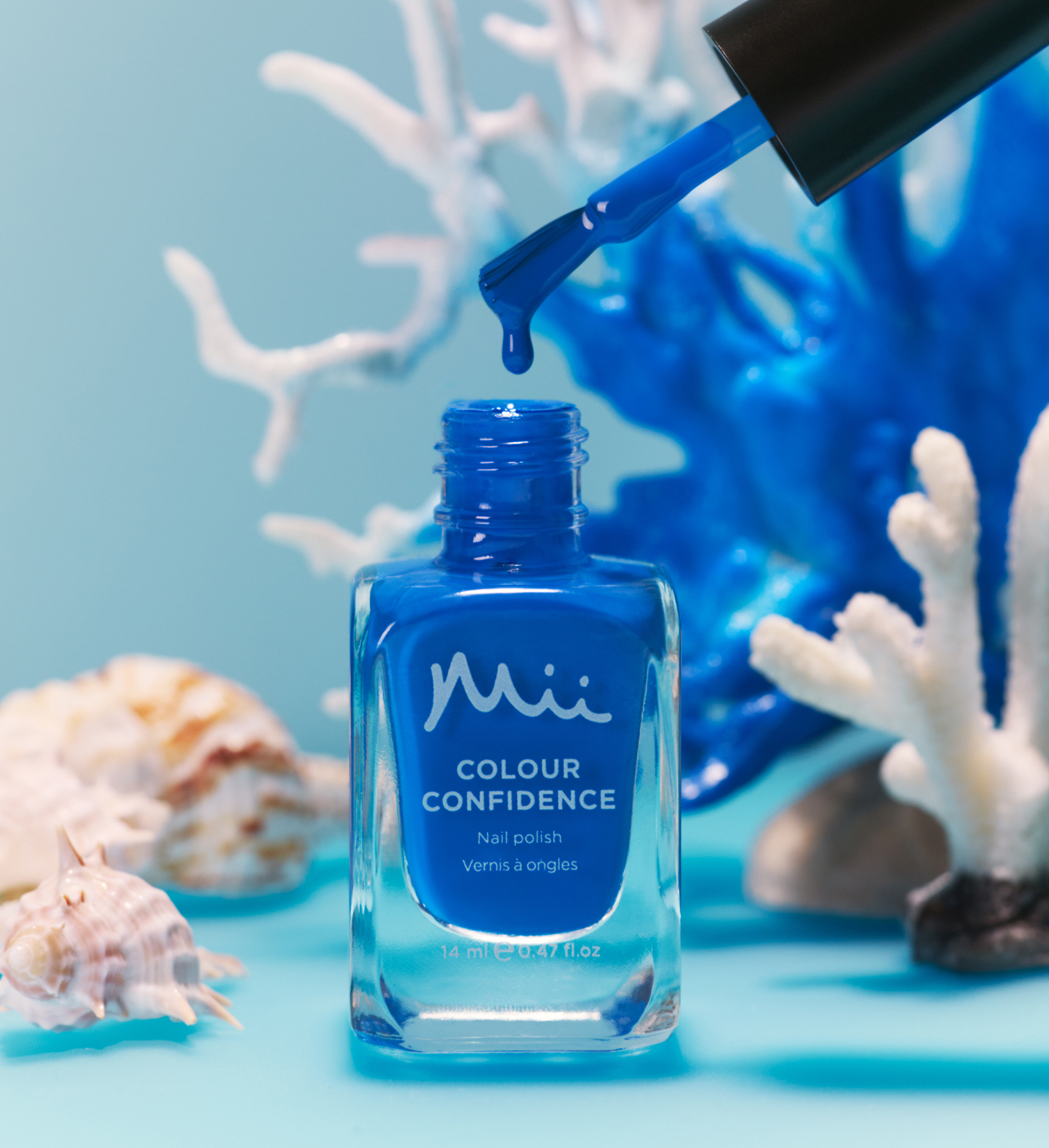 Dripping shot of Ocean Dip Colour Confidence Nail Polish against a blue background with white plants