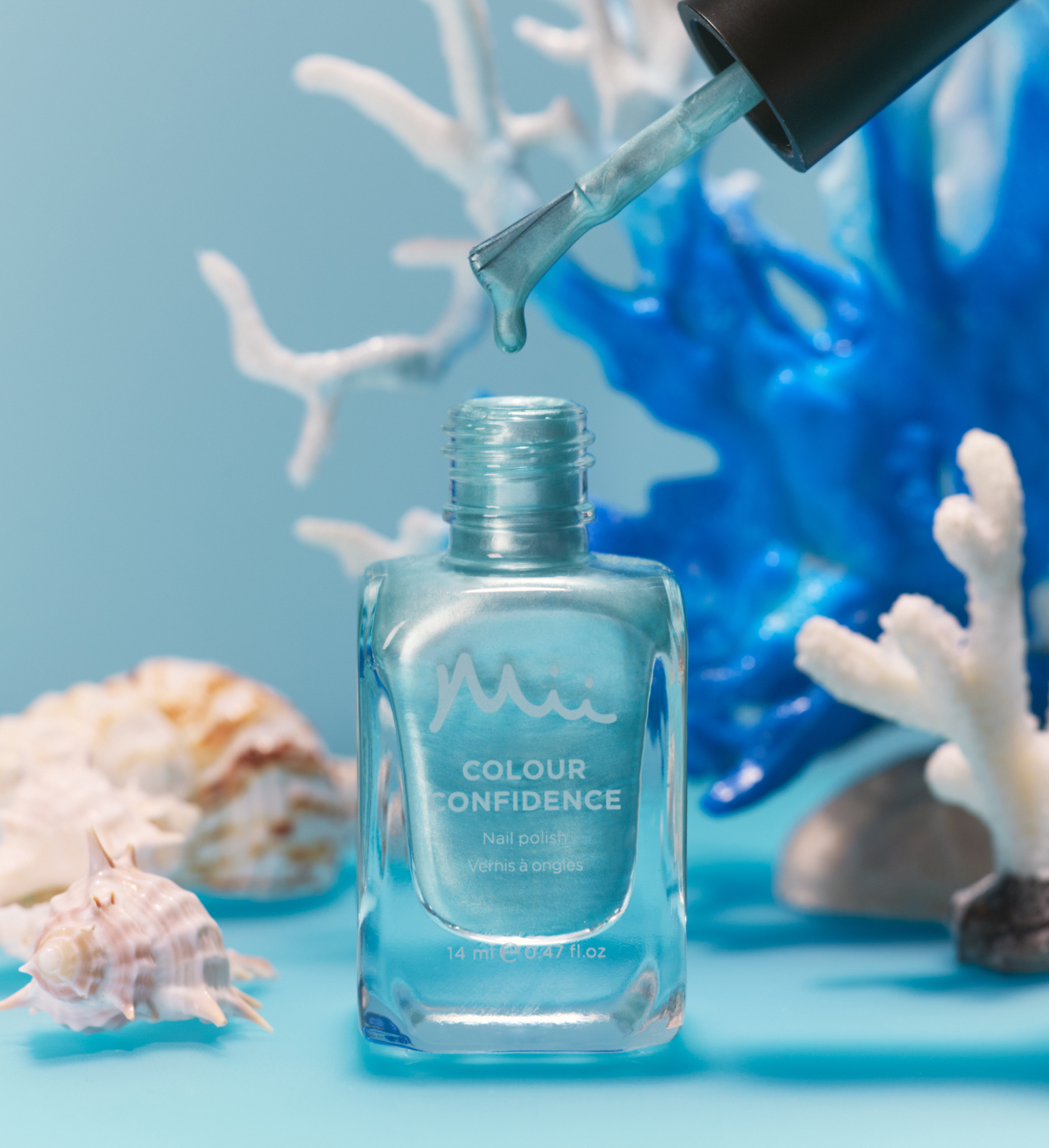 Dripping shot of Sea Glass Colour Confidence Nail Polish against a blue background with white plants
